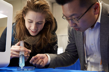 A woman and man view a petri dish.